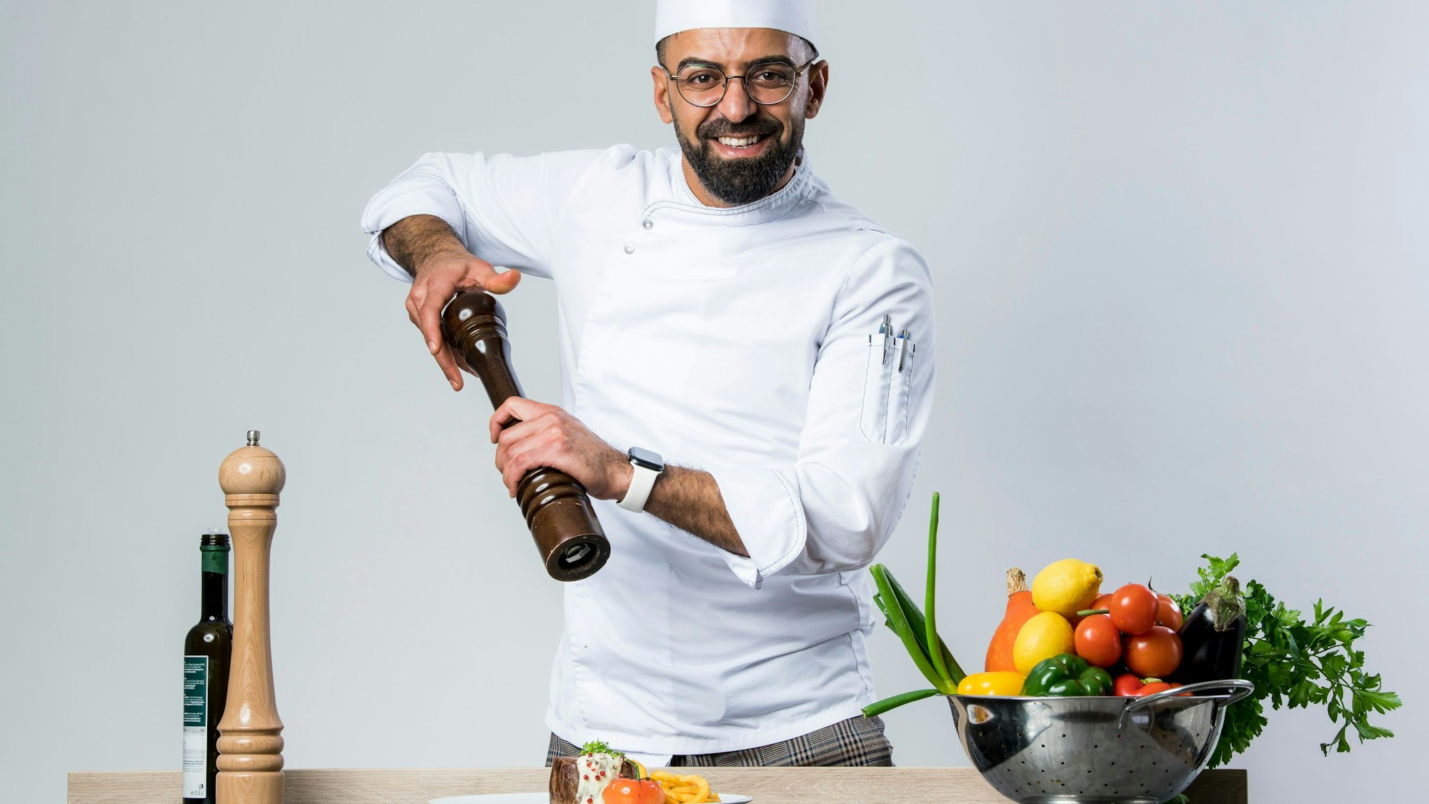 Zu sehen ist ein Koch, der eine Pfeffermühle bedient.