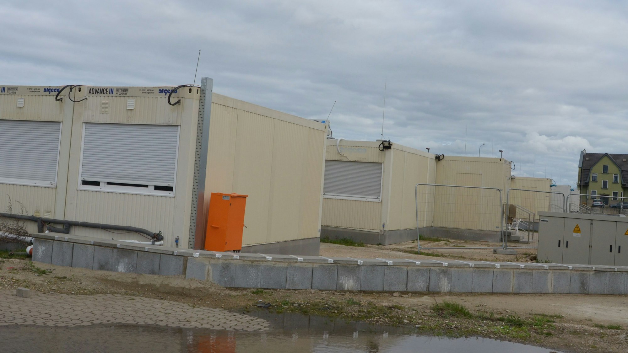 Eine Reihe von Wohncontainern für Geflüchtete, die Rolläden sind geschlossen.