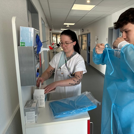 Katharina Hinter und Tobias Theysen beim Anlegen von Schutzkleidung.