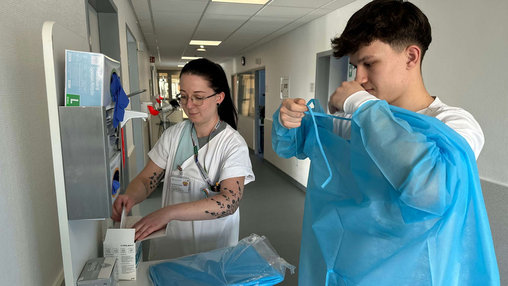 Katharina Hinter und Tobias Theysen beim Anlegen von Schutzkleidung.