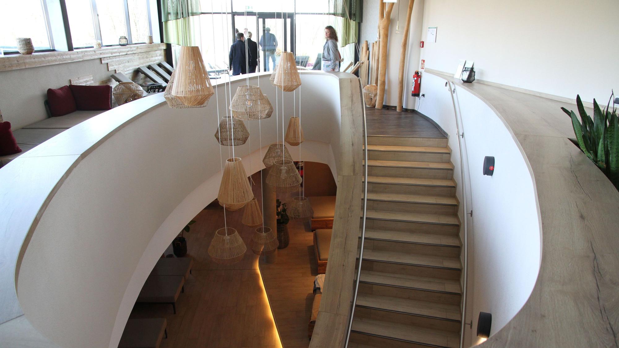 Eine geschwungene Treppe führt aus dem Erdgeschoss einer Sauna in das Obergeschoss.