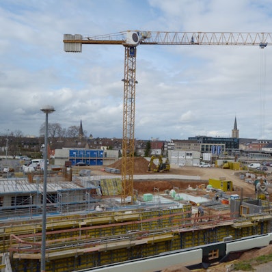 Das Eckgrundstück Roitzheimer Straße/An der Vogelrute ist eine Großbaustelle, im Hintergrund erkennt man den Bahnhof und die drei Kirchen in der Euskirchener Innenstadt.