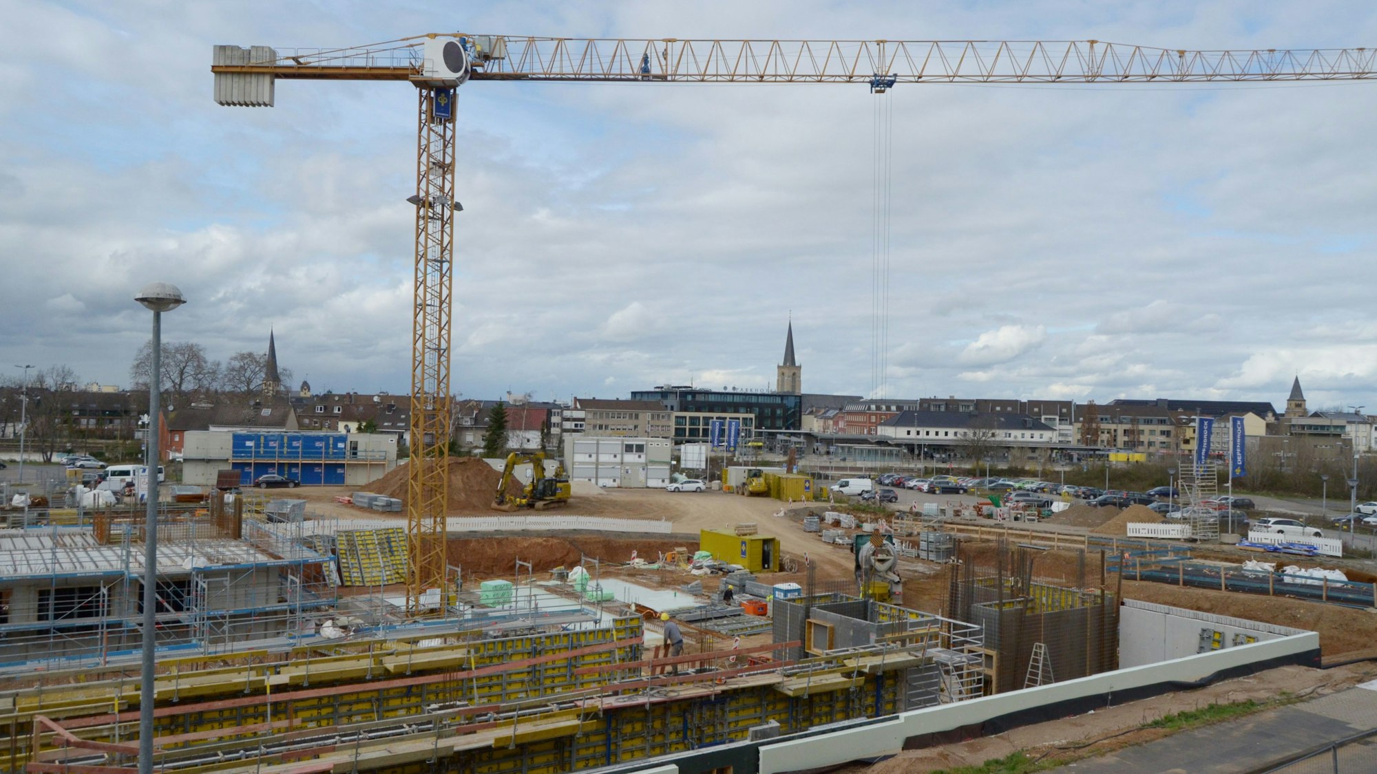 Das Eckgrundstück Roitzheimer Straße/An der Vogelrute ist eine Großbaustelle, im Hintergrund erkennt man den Bahnhof und die drei Kirchen in der Euskirchener Innenstadt.