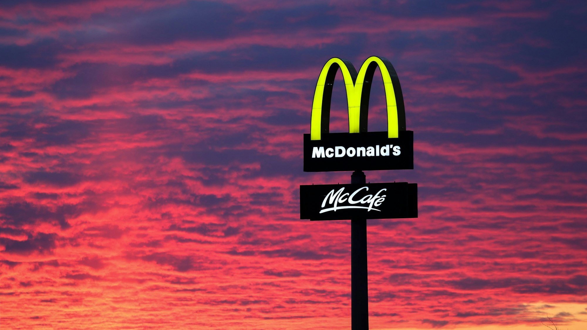 Der Abendhimmel leuchtet hinter einem McDonald's-Logo.