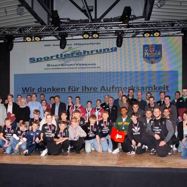Sportlerinnen und Sportler stehen in einer Gruppe zusammen.