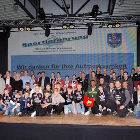 Sportlerinnen und Sportler stehen in einer Gruppe zusammen.