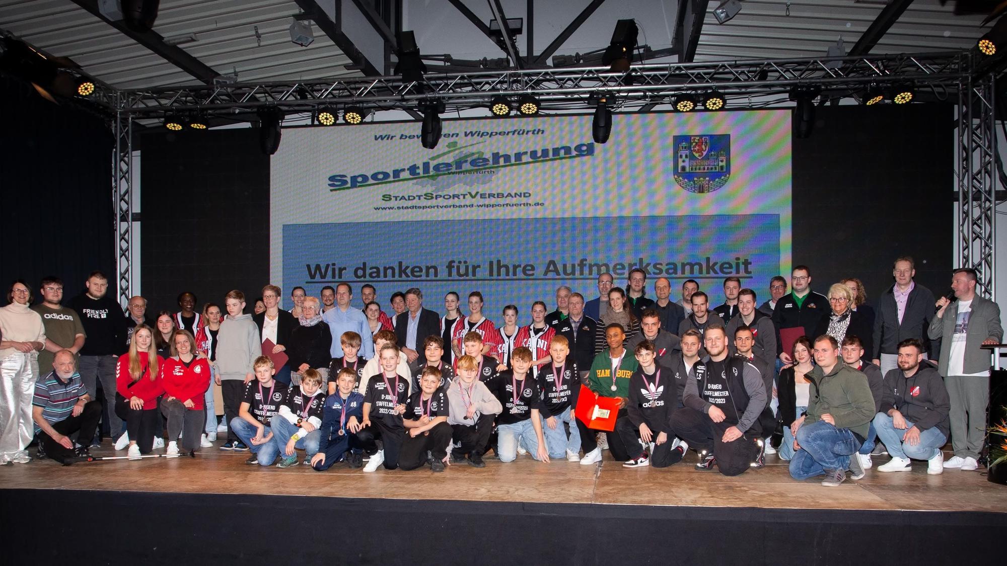 Sportlerinnen und Sportler stehen in einer Gruppe zusammen.