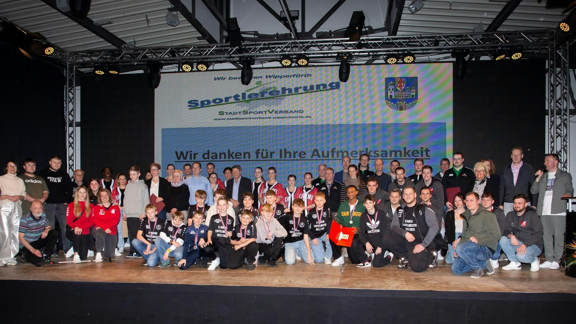 Sportlerinnen und Sportler stehen in einer Gruppe zusammen.