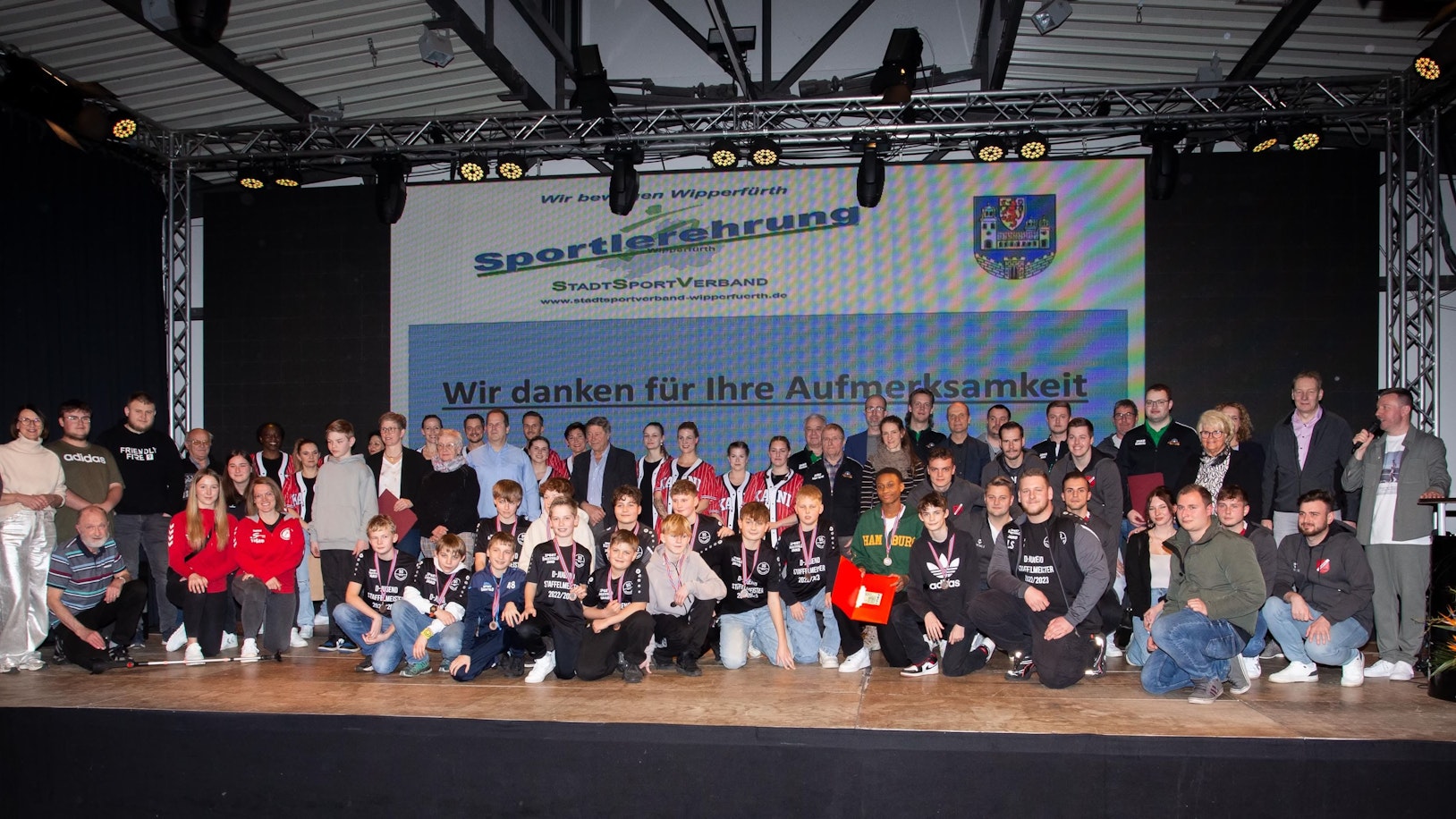 Sportlerinnen und Sportler stehen in einer Gruppe zusammen.