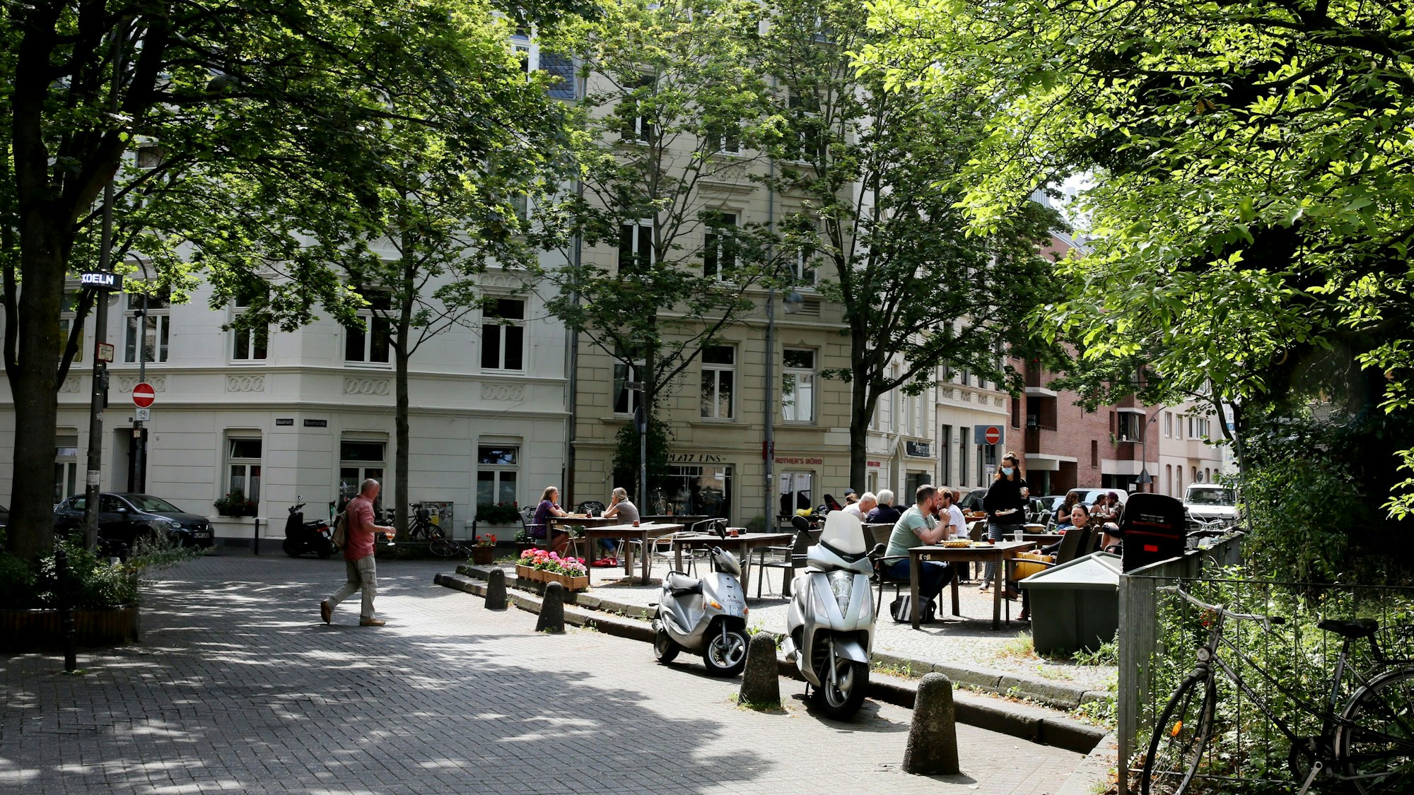 Blick auf einen etwas erhöhten Platz, auf Tische und Stühle eines Cafés stehen