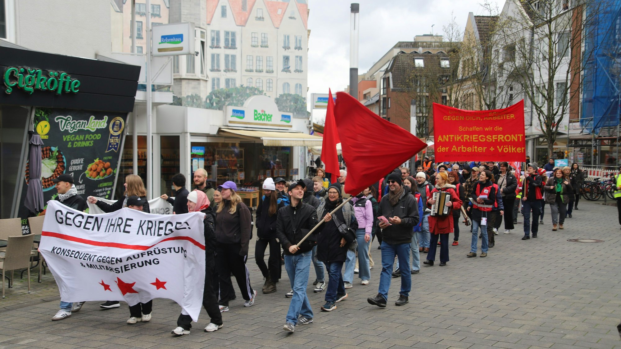 Menschen, zum Teil Transparente haltend, ziehen durch eine Straße..