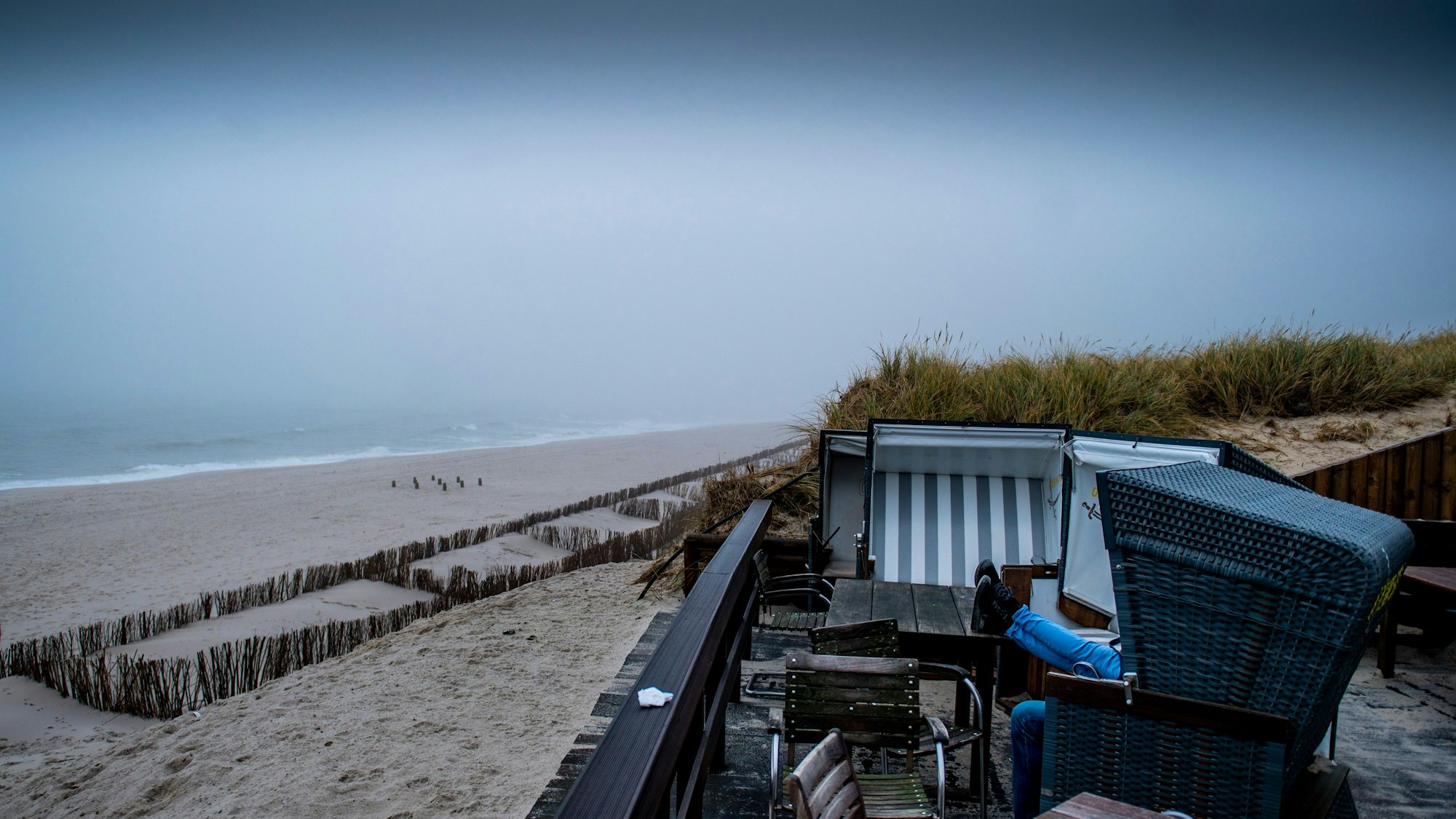 Zwei Besucher sitzen in einem Strandkorb am Strand von Rantum auf Sylt.