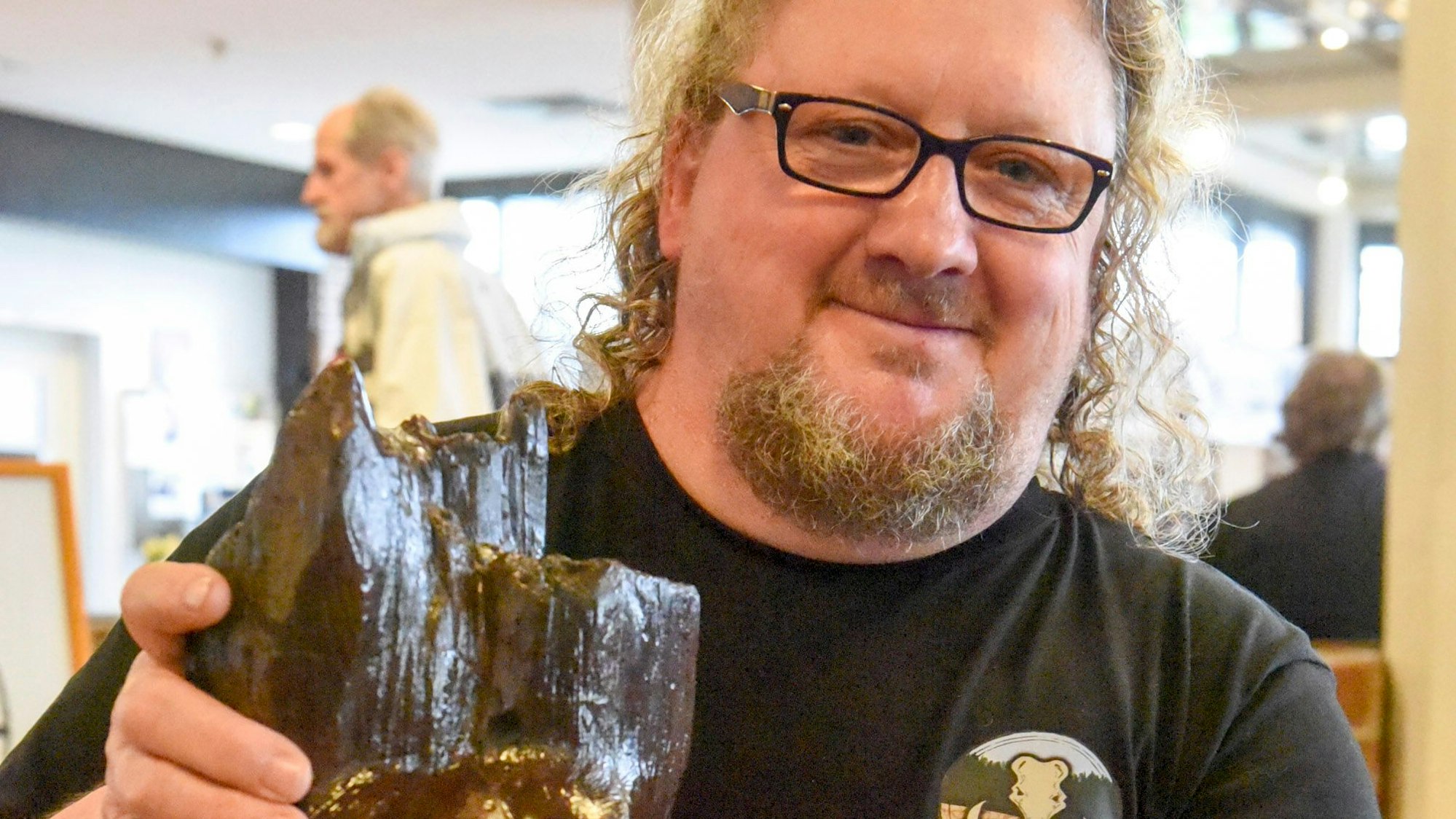 Auf dem Bild ist ein Künstler mit einer Skulptur zu sehen.