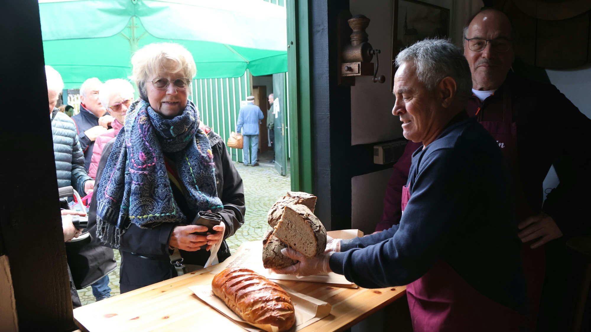 Ein Mann packt einer Frau Brot ein.