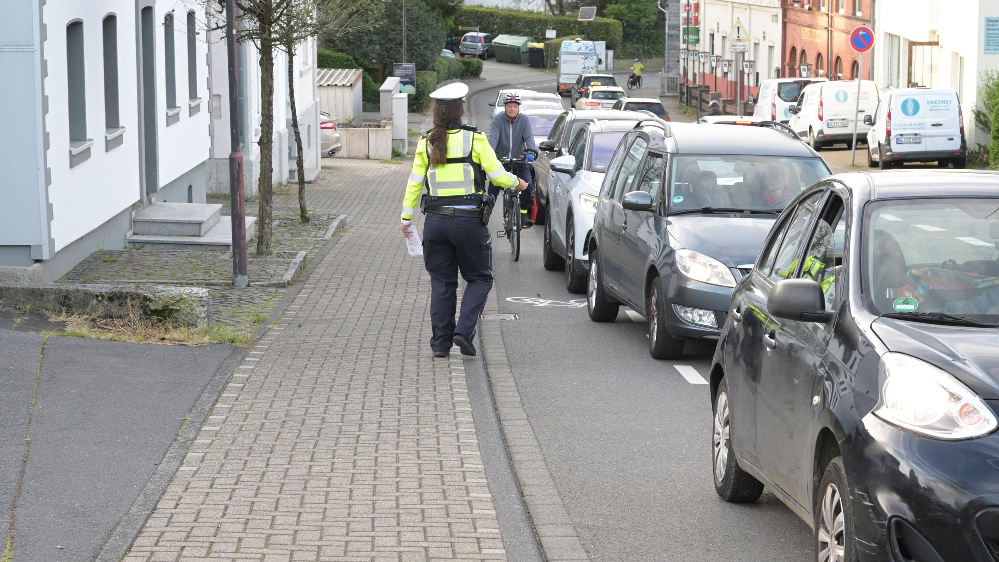 Bei der Aktion "Mehr Miteinander im Verkehr" beobachtet eine Polizistin den Rad-Schutzstreifen
auf der Bensberger Straße in Forsbach.