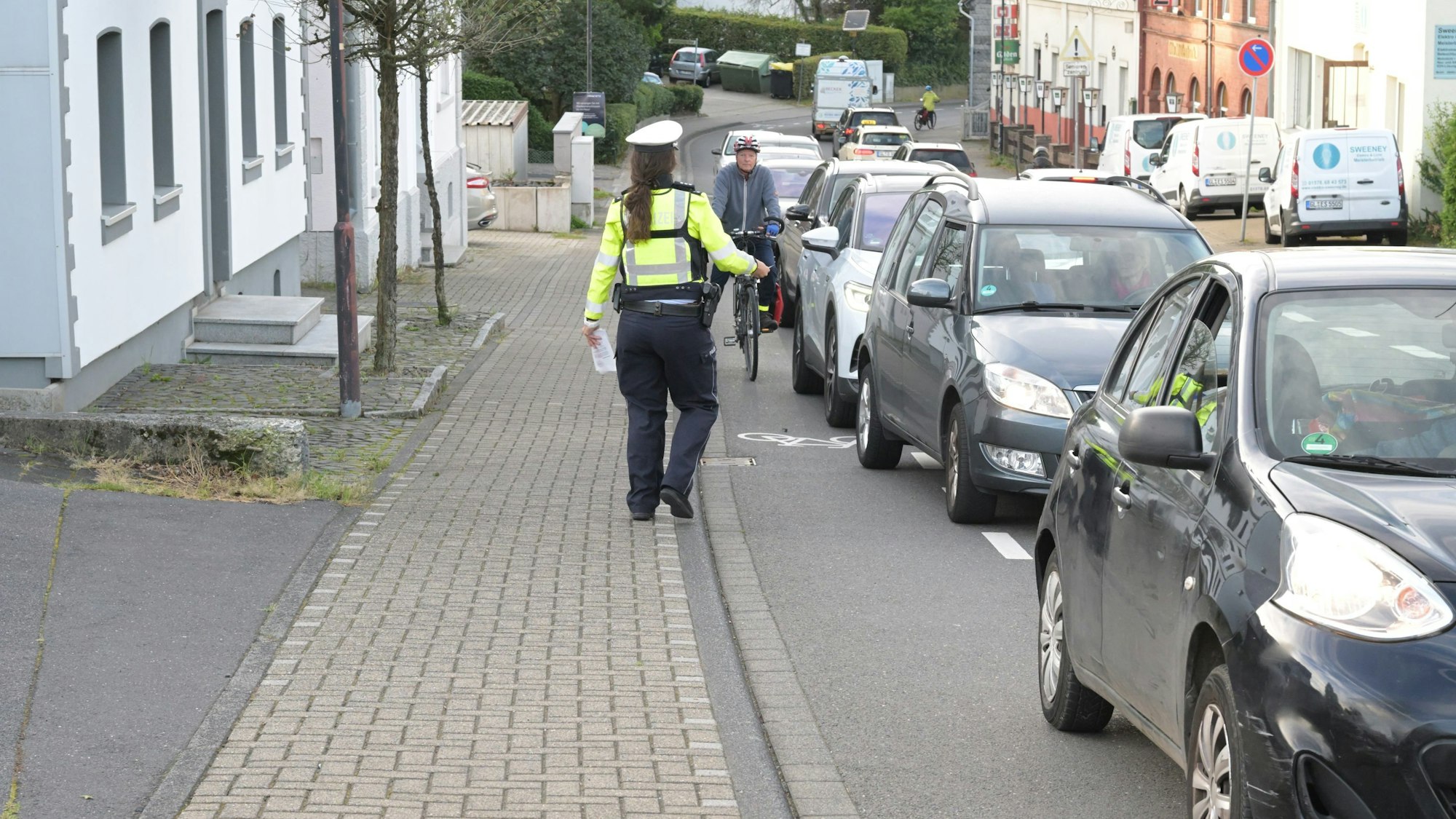 Bei der Aktion "Mehr Miteinander im Verkehr" beobachtet eine Polizistin den Rad-Schutzstreifen
auf der Bensberger Straße in Forsbach.