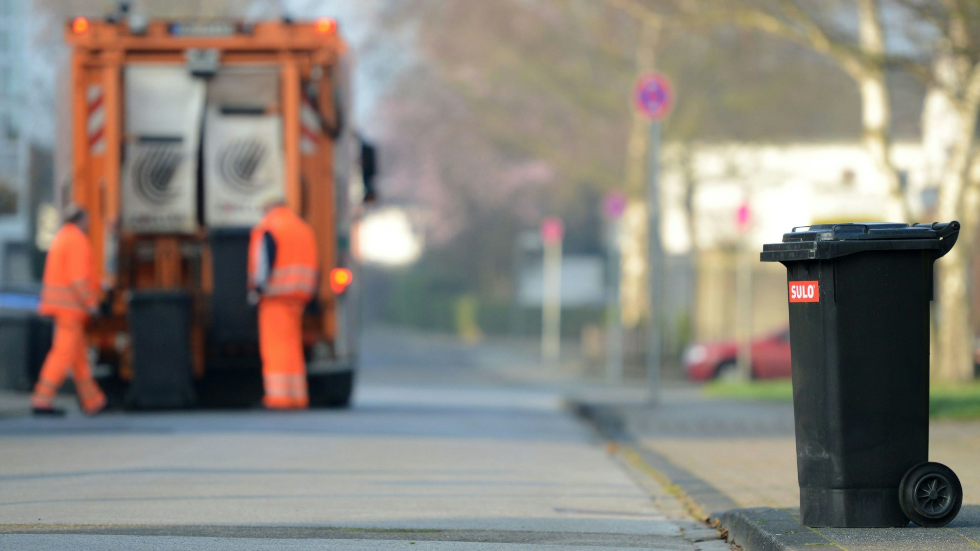 Zwei Männer von der Müllabfuhr entleeren Graue Tonnen (Symbolfoto).