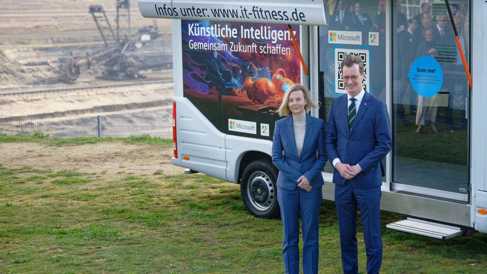 Elsdorf: Marianne Janik (l), Vorsitzende der Geschäftsführung von Microsoft Deutschland, und Hendrik Wüst, Ministerpräsident des Landes Nordrhein-Westfalen (CDU), stehen vor einer Pressekonferenz zum Thema «Von der Kohle zur KI» am Rand des Tagebau Hambach vor einem Fahrzeug, mit dem für KI-Fortbildung geworben wird.