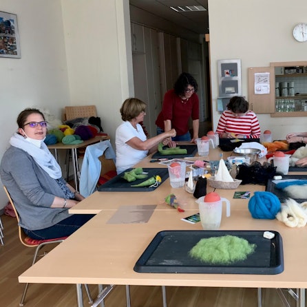 Das Foto zeigt Menschen, die an einem großen Tisch sitzen und basteln.