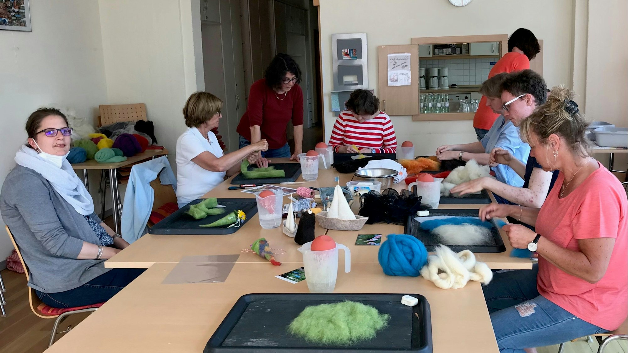Das Foto zeigt Menschen, die an einem großen Tisch sitzen und basteln.