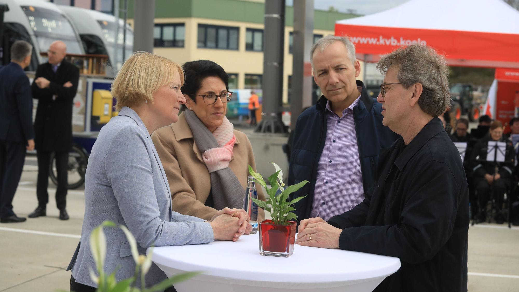 Zwei Frauen und zwei Männer stehen an einem Stehtisch.