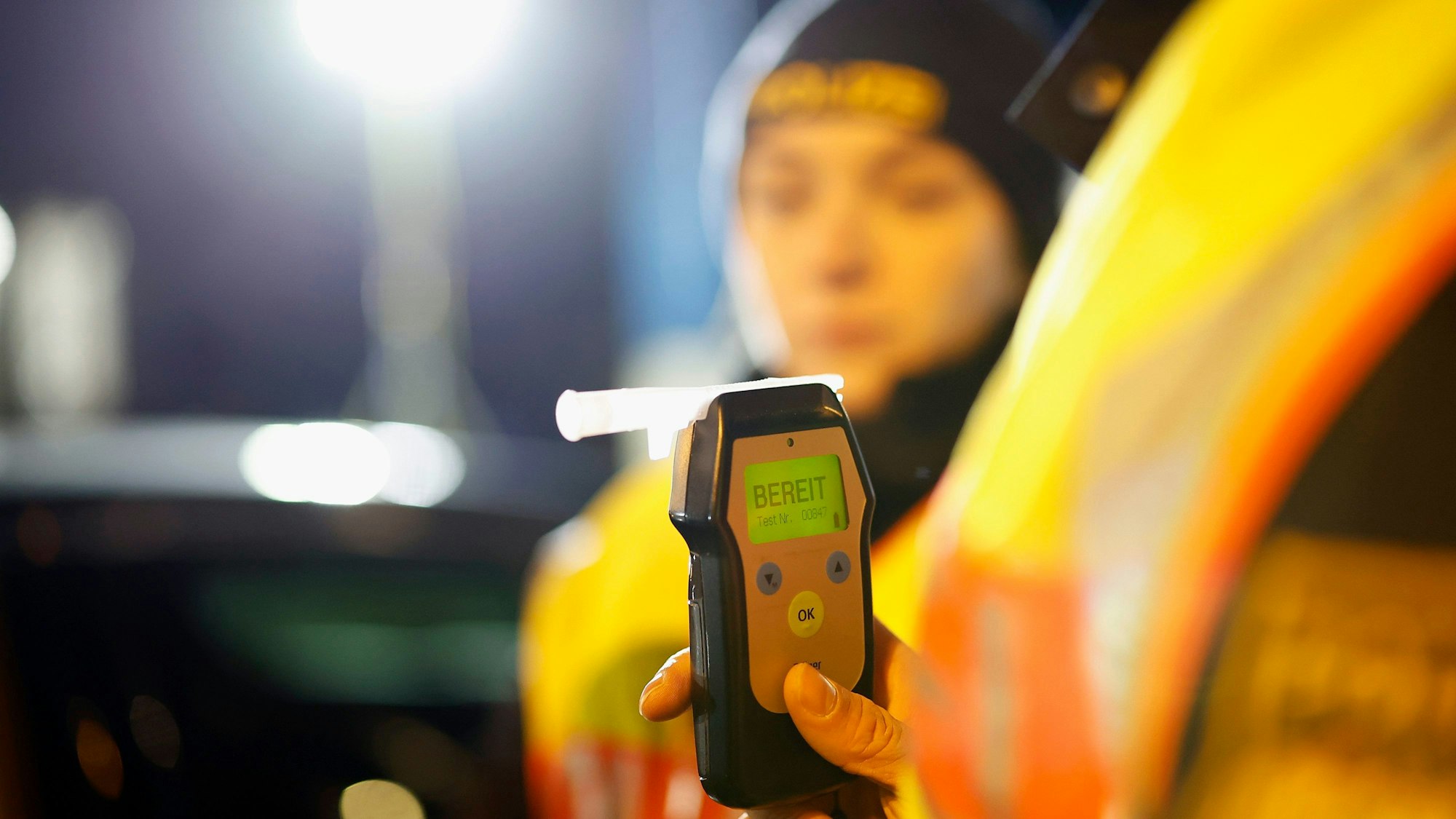Eine Polizistin misst den Atemalkoholgehalt eines Autofahrers mit einem Alkoholtester, um festzustellen, ob er möglicherweise unter Alkoholeinfluss steht.