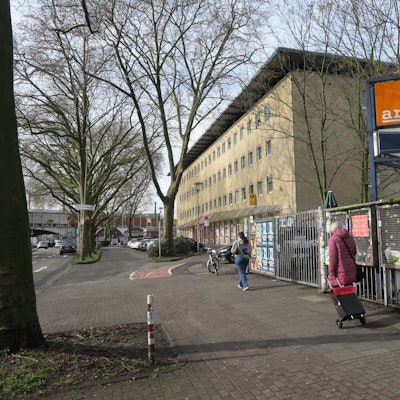 Blick auf ein mehrgeschossiges Gebäude mit gelber Fassade, im Vordergrund ist der Eingang zum Artheater.