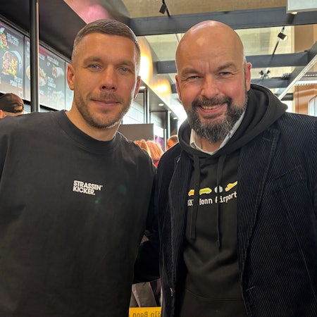 Thilo Schmid, Vorsitzender der Geschäftsführung der Flughafen Köln/Bonn GmbH freut sich mit Lukas Podolski über die neue Mangal-Döner Filiale.