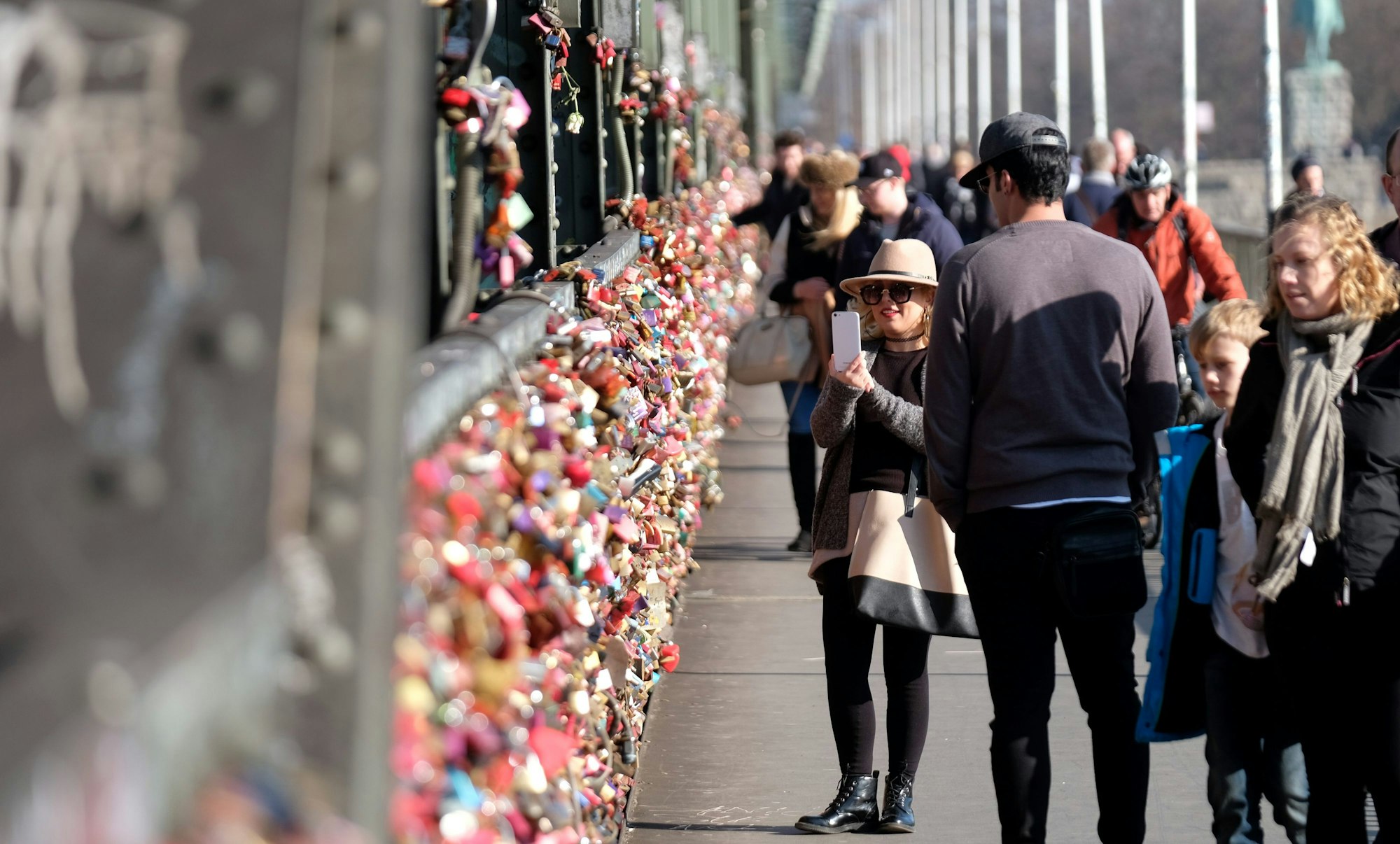Menschen betrachten die Liebesschlösser an der  Hohenzollernbrücke.