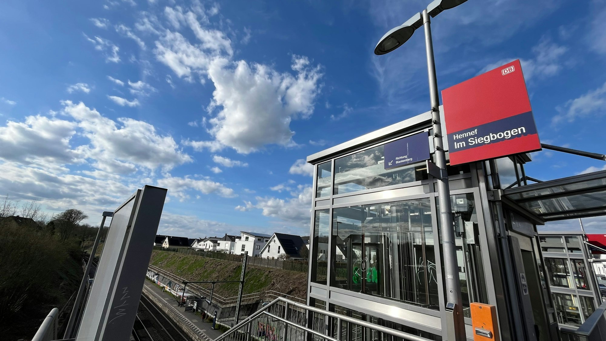 Ein gläserner Aufzug oberhalb des Bahnsteigs.