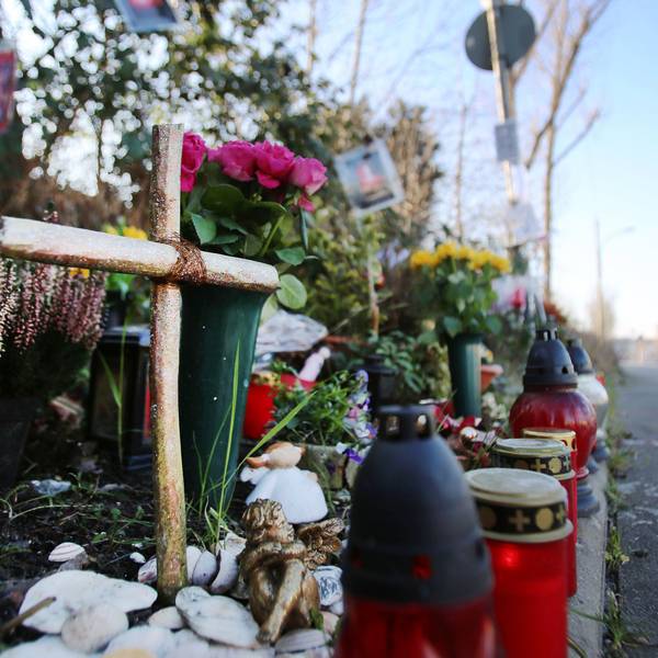 Am Straßenrand steht ein Kreuz und Grablichter.