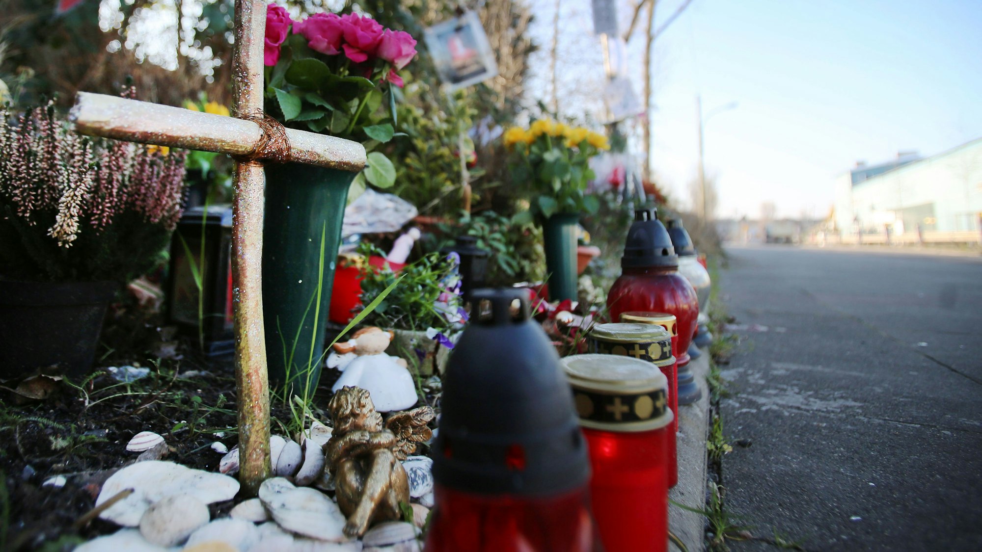 Am Straßenrand steht ein Kreuz und Grablichter.