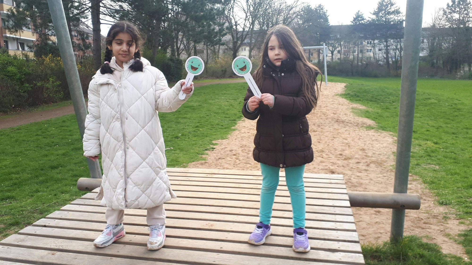 Zwei Mädchen, die sich an der Veedels-Aktion „Hey Nippes!“ beteiligen. Der Spielplatz an der Vogesenstraße, im Hintergrund die Seilbahn.
