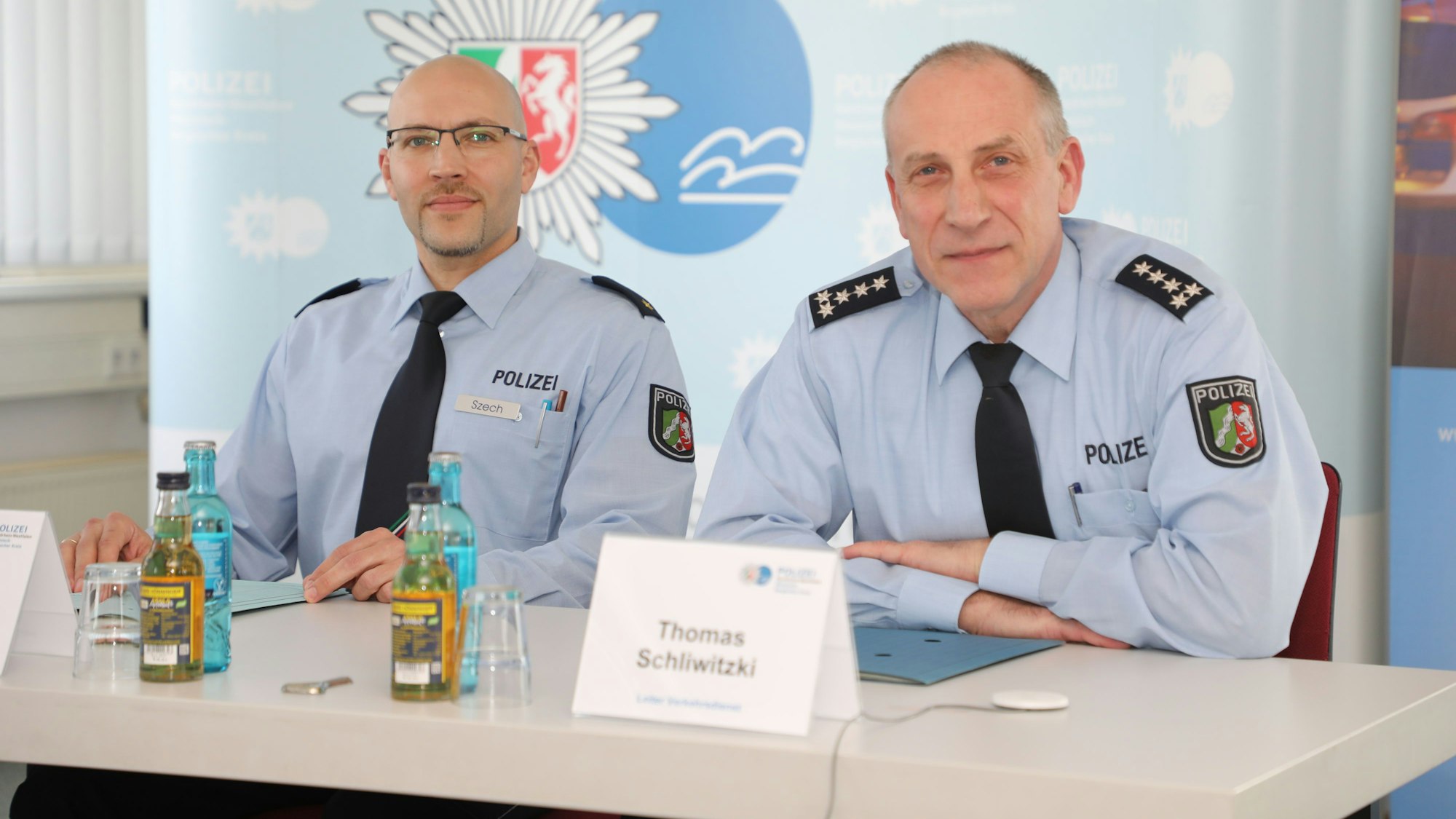 Zwei Polizeibeamte sitzen bei einer Pressekonferenz in der Kreispolizeibehörde des Rheinisch-Bergischen Kreises an einem Tisch.