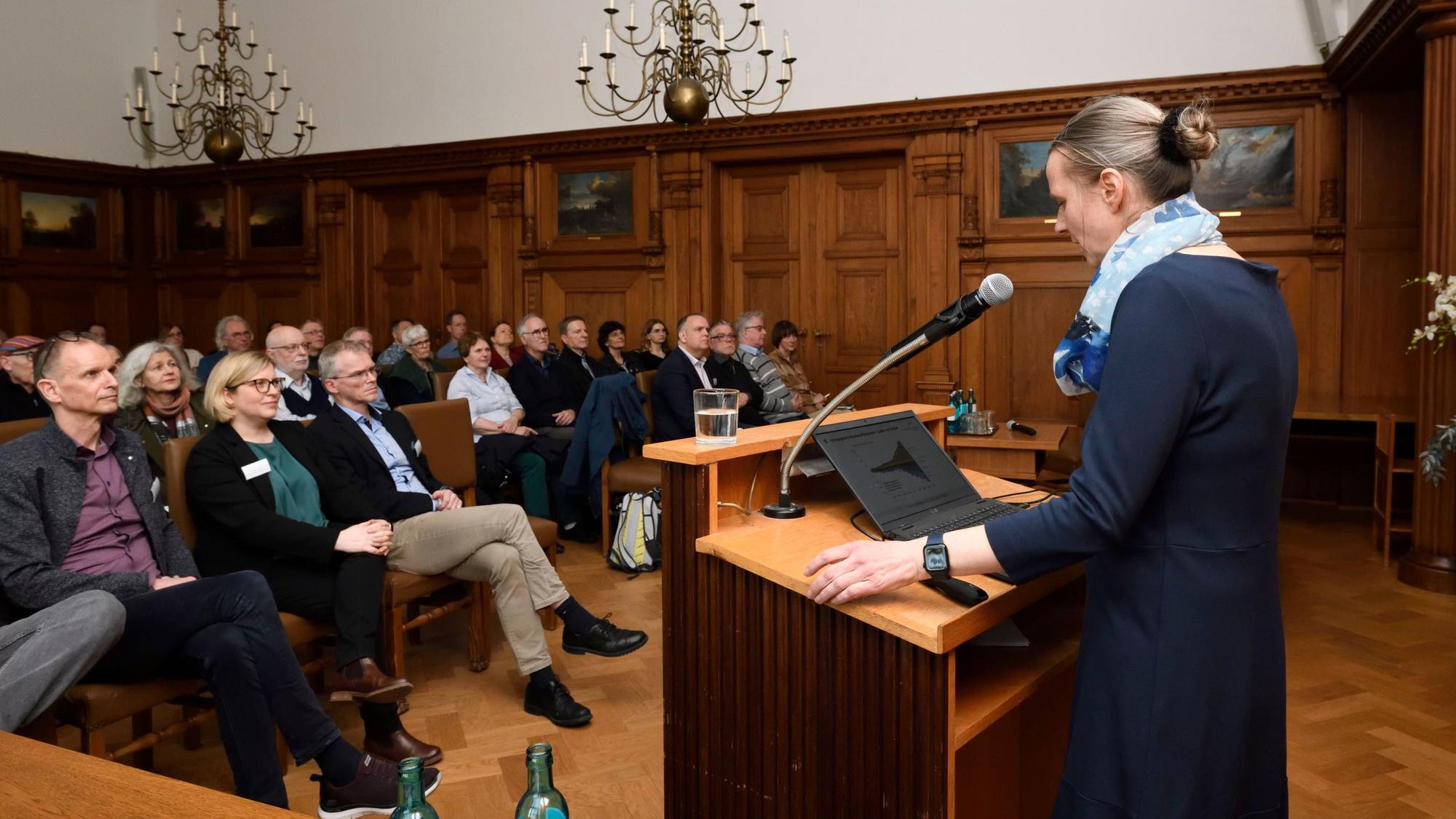 Rednerin Diana Rechid steht am Rednerpult im Ratsaal des Rathauses Bergisch Gladbach. Sie spricht zum Integrierten Klimaschutzkonzept.