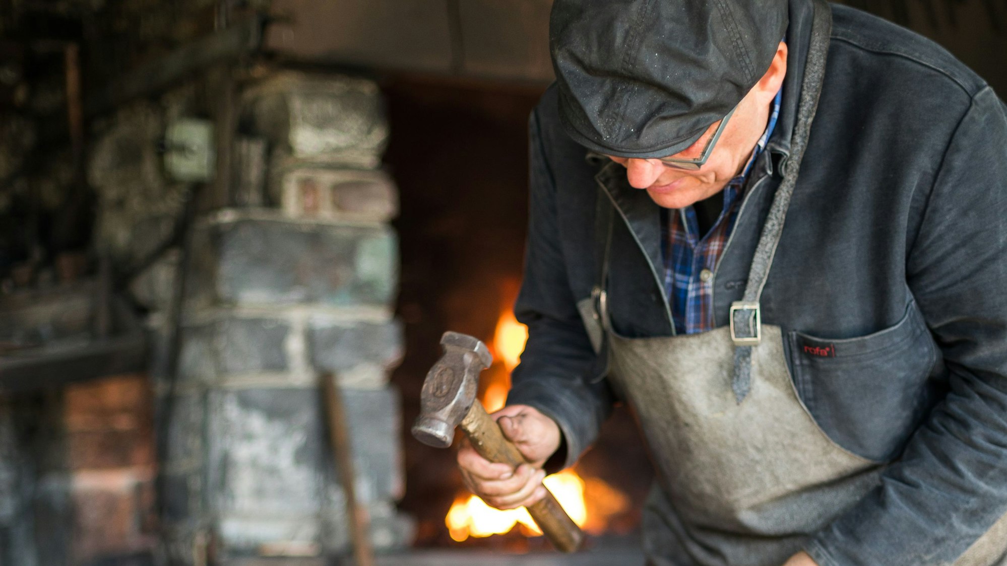 Schmied mit einem Hammer in der Hand vor einem Feuer
