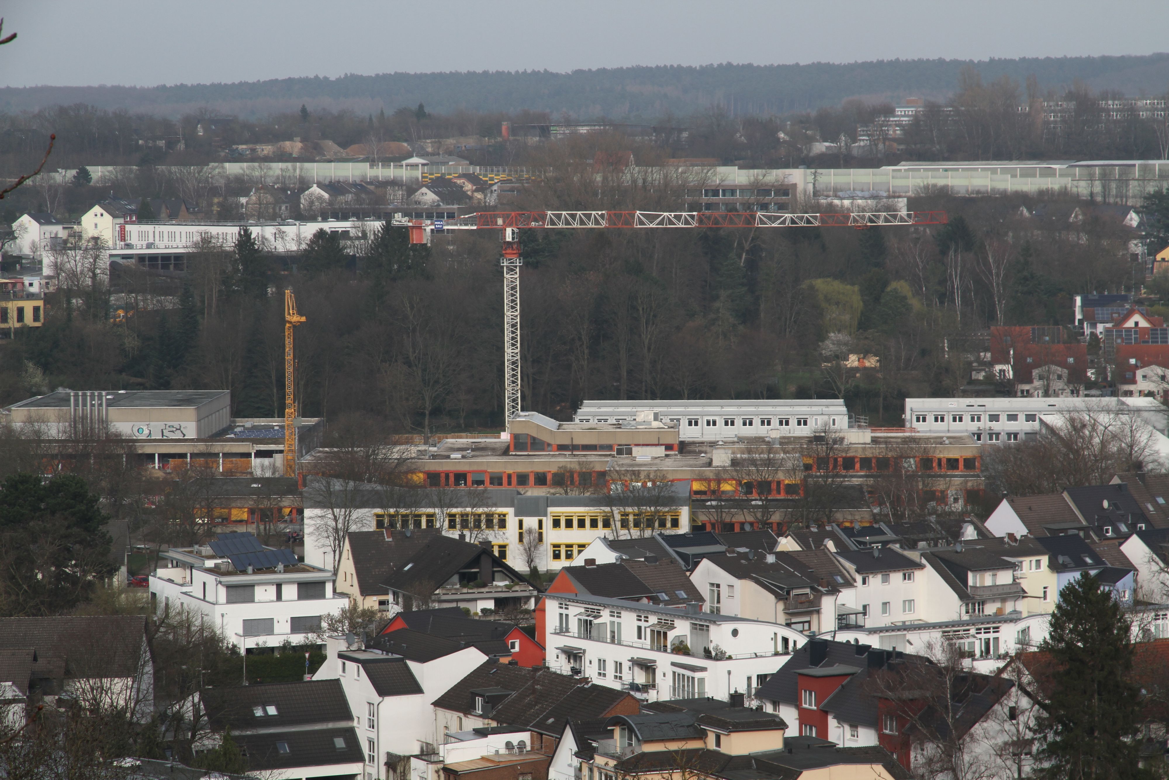 Zwei Baukräne über einem Schulzentrum
