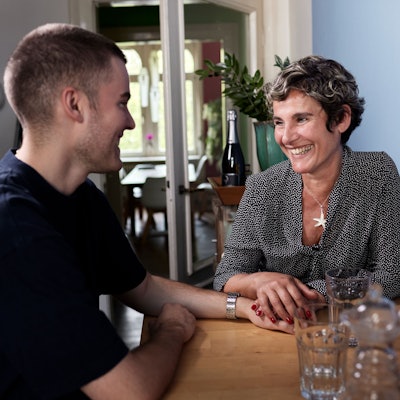 Lächelnde ältere Frau und junger Mann gucken sich an