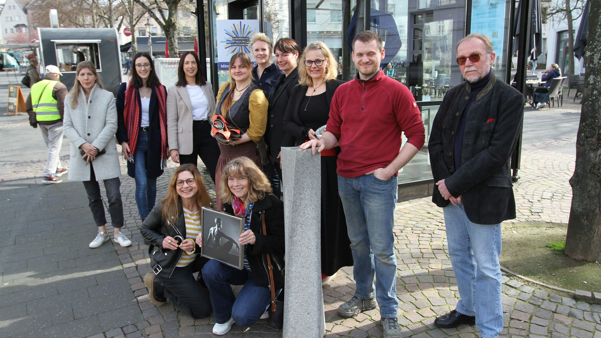 Eine Gruppe von Frauen und Männern vor einem Glaspavillon