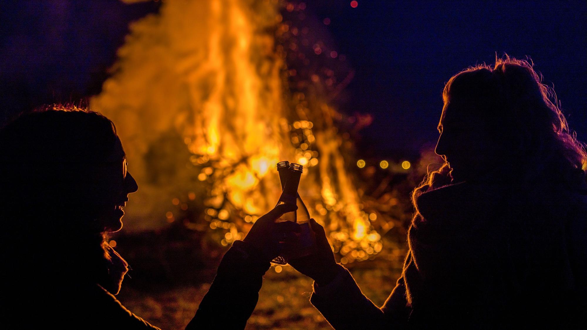 Besucherinnen prosten einander zu, während sie sich das Branitzer Osterfeuer anschauen.