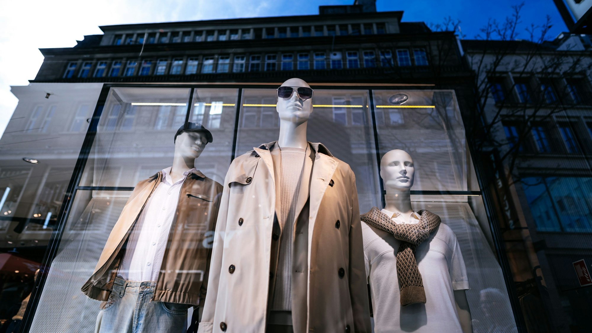 Drei Schaufensterpuppen stehen in einem Schaufenster.