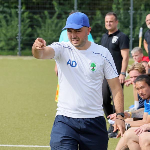 Das Bild zeigt Trainer Albert Deuker, der mit der Hand in Richtung Fußballtor zeigt.