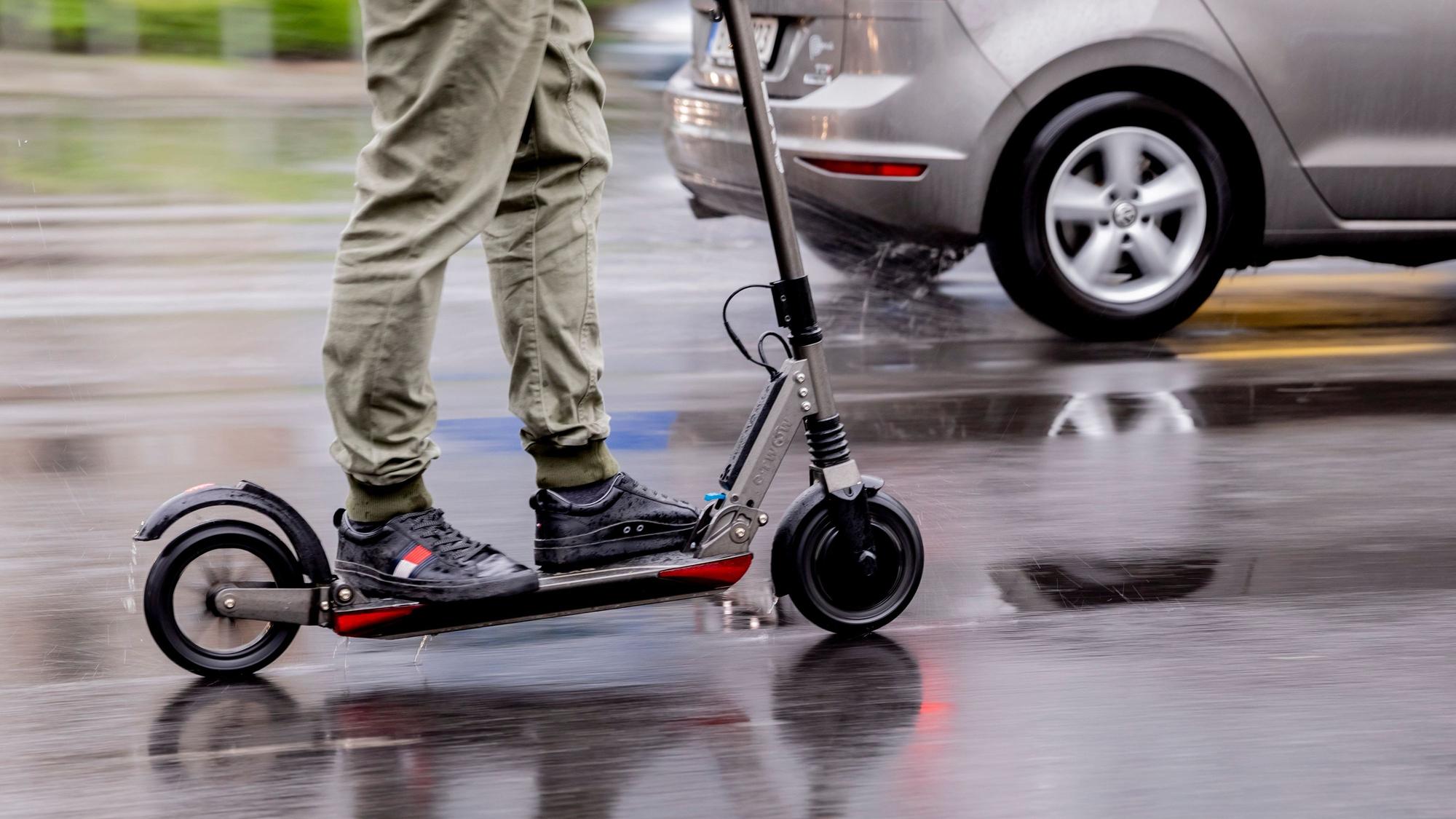 Ein Mann fährt mit einem E-Scooter auf der Straße.