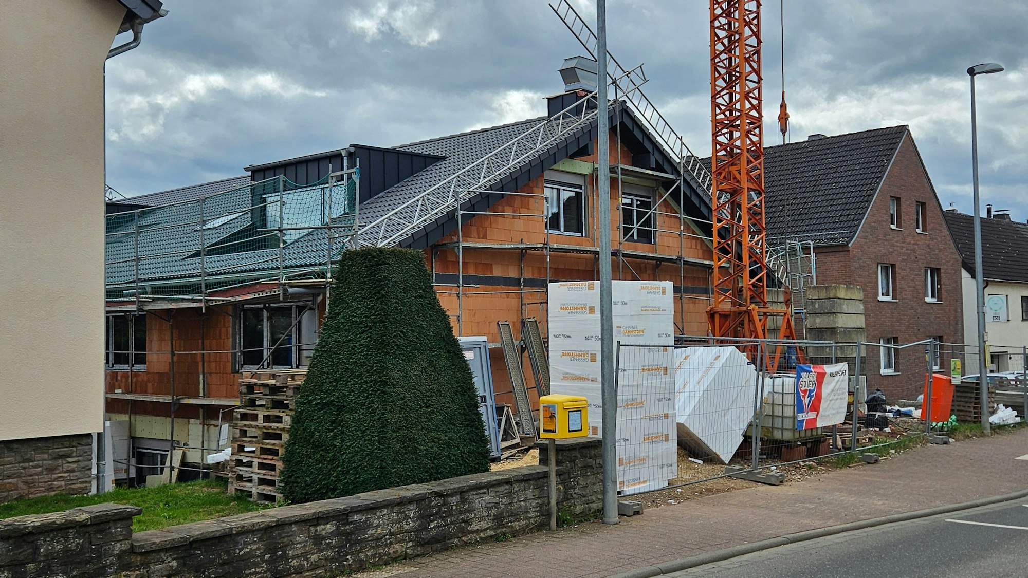 Blick auf einen eingerüsteten Neubau zwischen zwei Bestandsbauten in Kall.