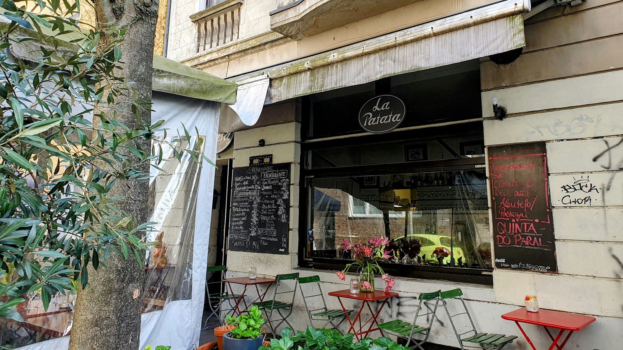 Das Restaurant La Patata von Außen mit bunten Tischen und Stühlen.