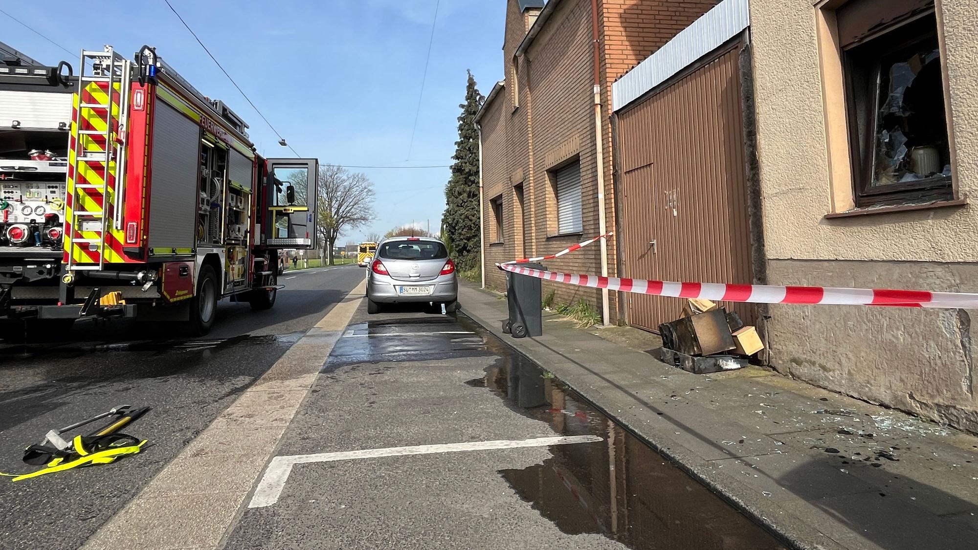 In einem Haus an der Hauptstraße in Troisdorf-Spich hat eine Küche gebrannt, Feuerwehrleute brachten die verbrannten Möbel ins Freie und sperrten den Bürgersteig mit Flatterband.