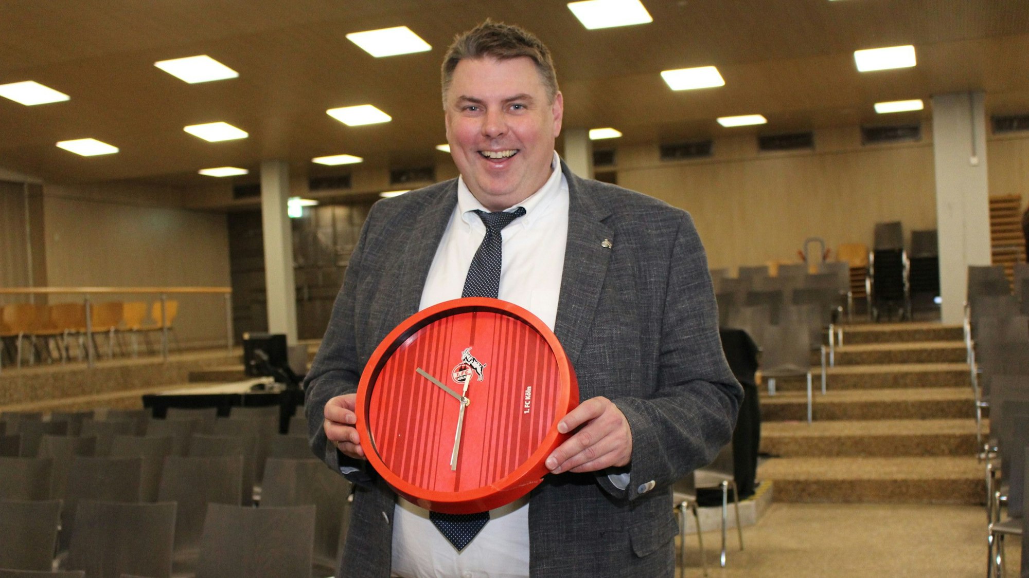 Michael Mombaur zeigt die reparierte rote Wanduhr mit dem Geißbock-Emblem.