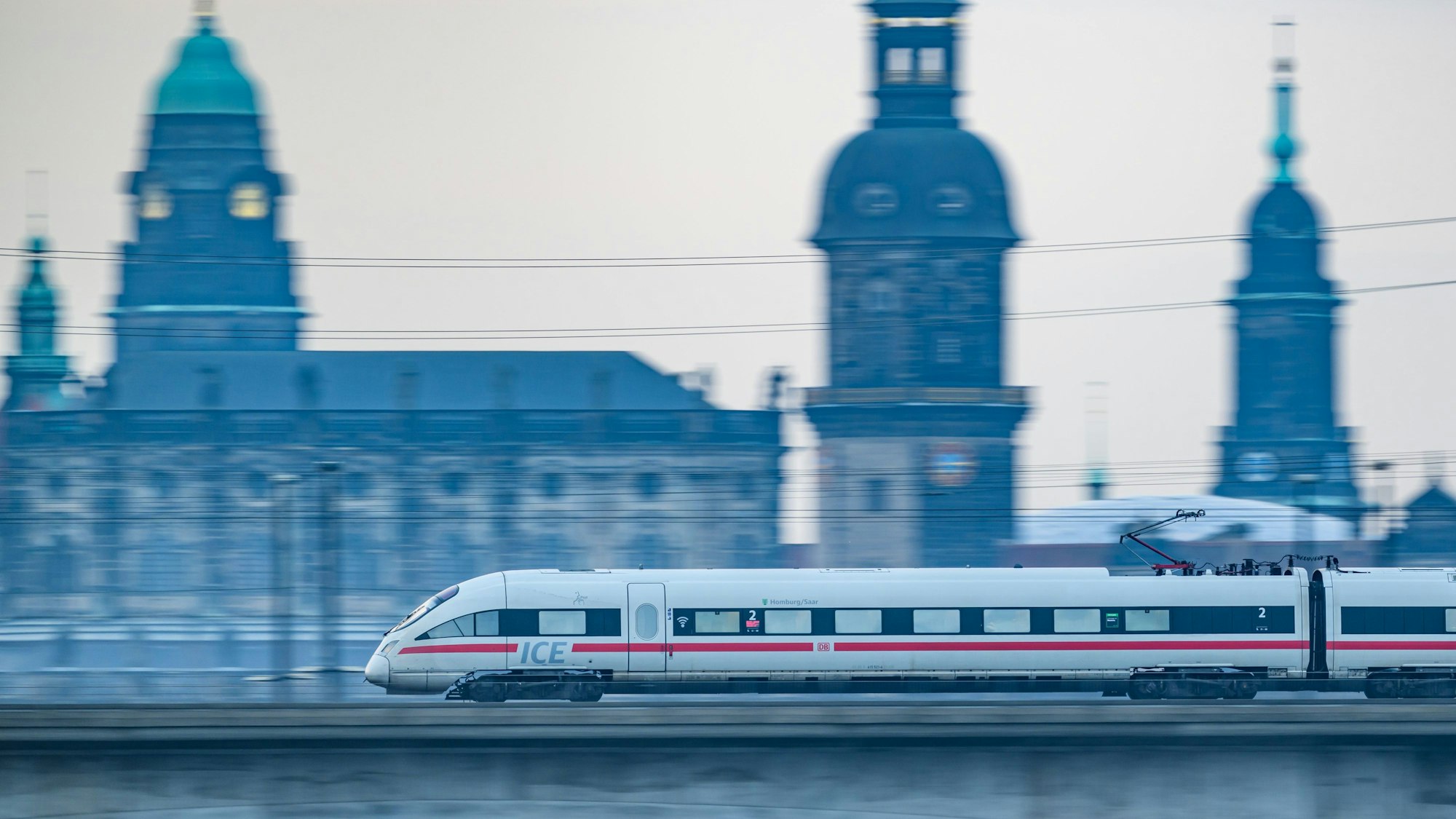 Ein ICE-Zug der Deutschen Bahn fährt am Morgen vor der Altstadtkulisse über die Marienbrücke.