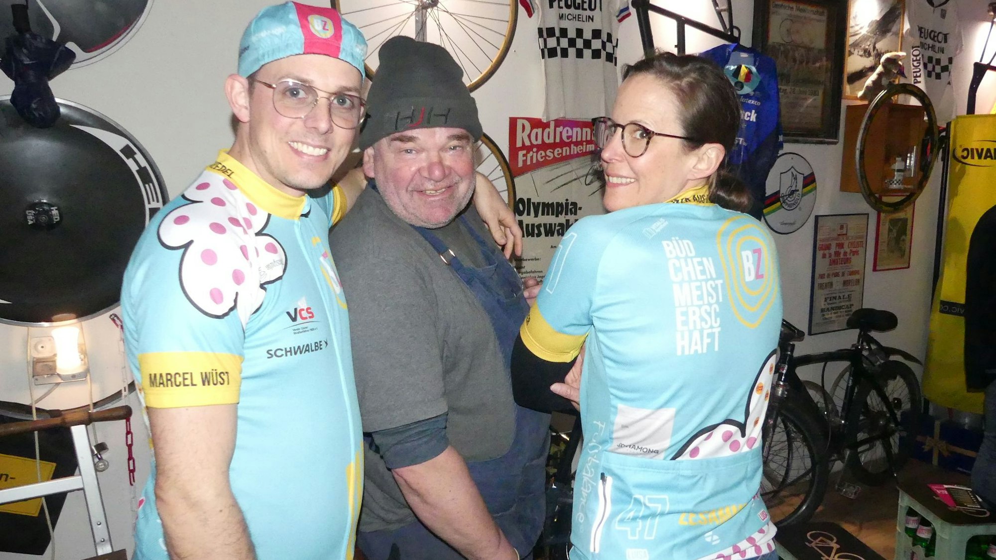 Oliver Zillger (v.l.), Hans-Jürgen Habetz und Luisa Bell präsentieren in der Werkstatt der „Radfabrik“ von Habetz das neue hellblaue Trikot für das Rad-Event in Bickendorf. Foto von Heribert Rösgen