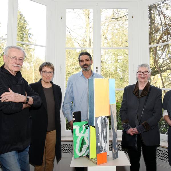Eine Gruppe steht im Halbkreis um ein Kunstobjekt.